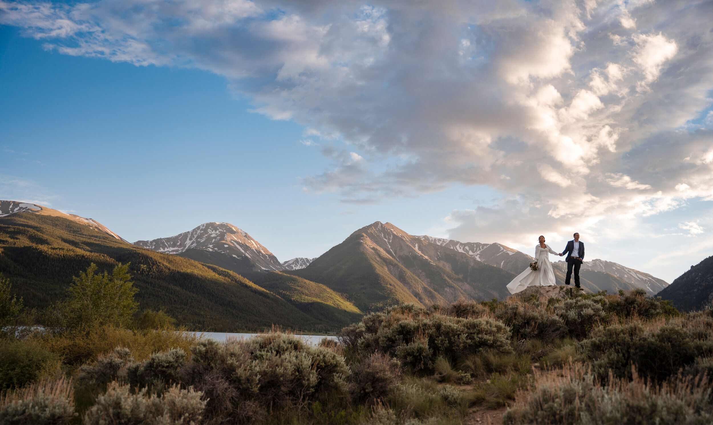 Couple on a ridge above a mountain lake at sunset