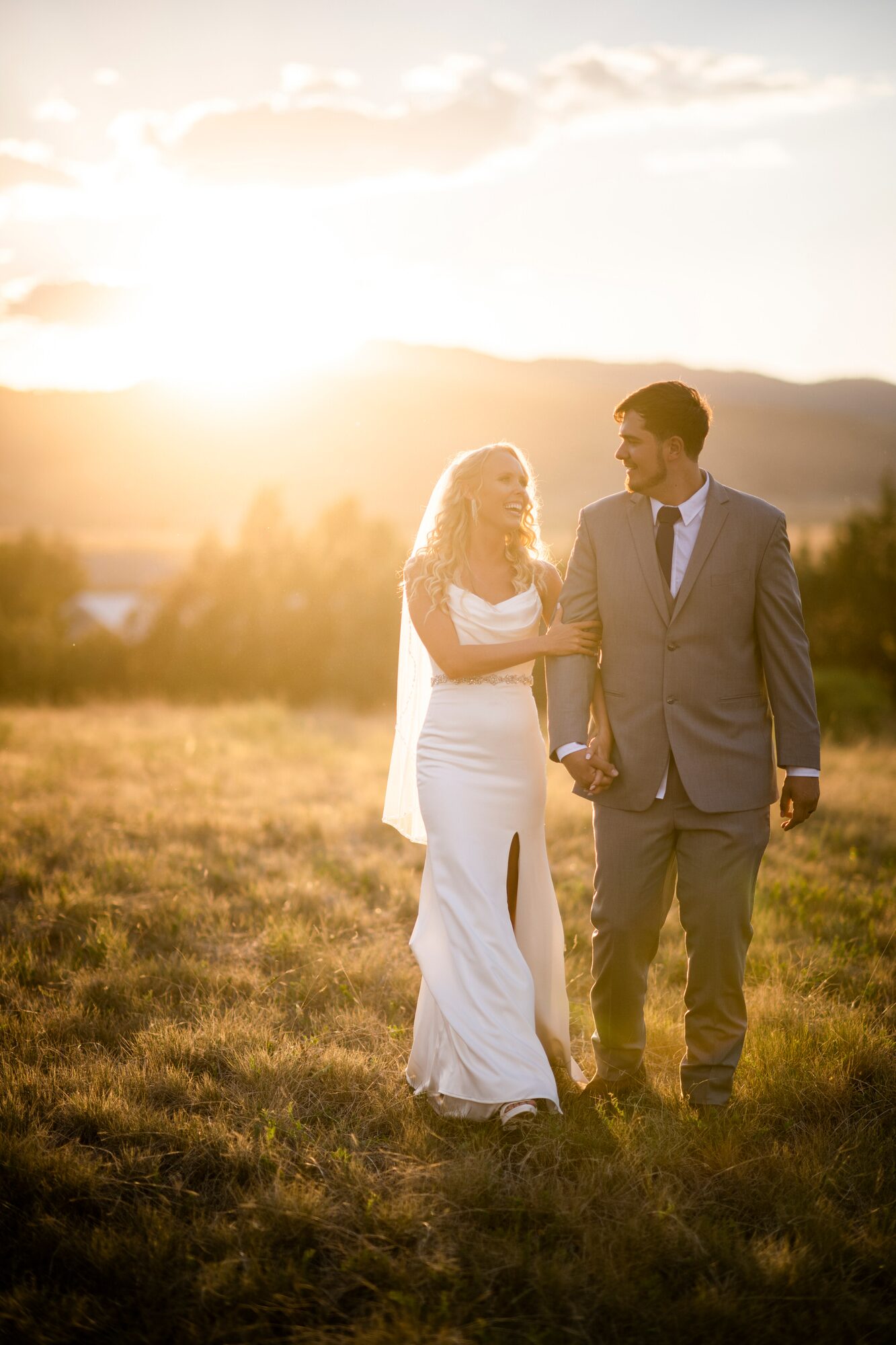 Couple walking hand in hand through a field at sunset